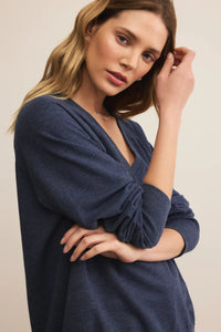 Woman wearing a blue dress against a beige background.