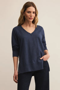 Woman wearing a navy blue sweater and pants on a beige background.