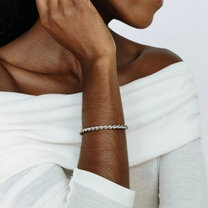 Woman wearing a white off-shoulder top with a close-up of her hand and bracelet.