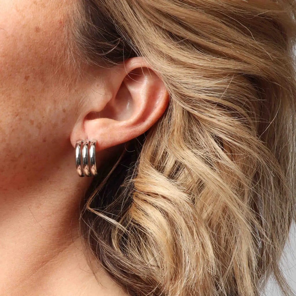 A close up of a woman wearing silver earrings.