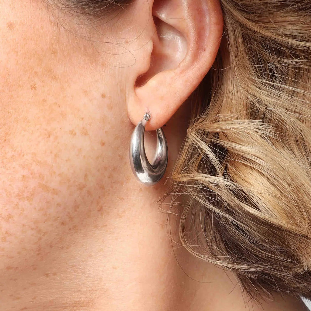 A close up of a woman wearing silver hoop earrings.