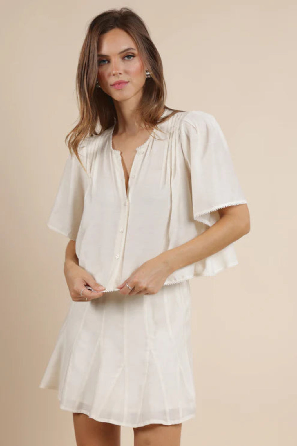 A woman wearing a flowy ivory top with a matching skirt. 