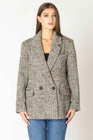 Woman wearing a tweed blazer and jeans.